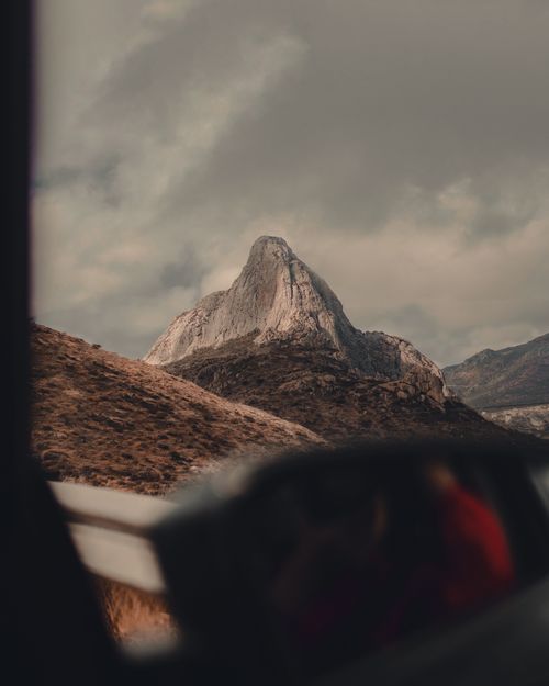 Free Dramatic view of Peña de Bernal, Mexico's monolith, seen from a car window. Stock Photo