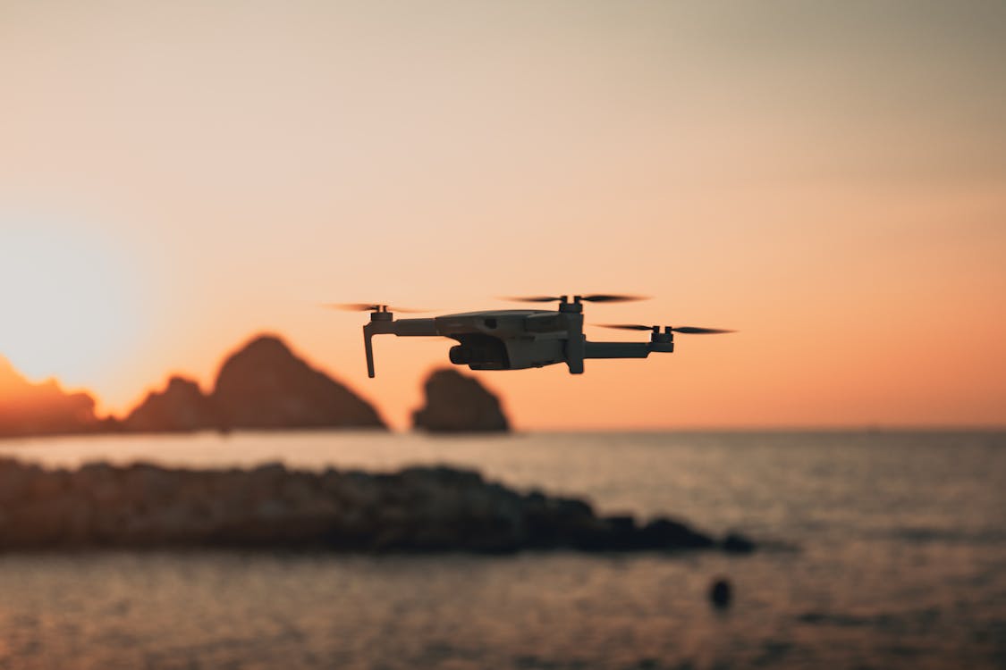Free A Drone Flying above the Shore at Sunset  Stock Photo