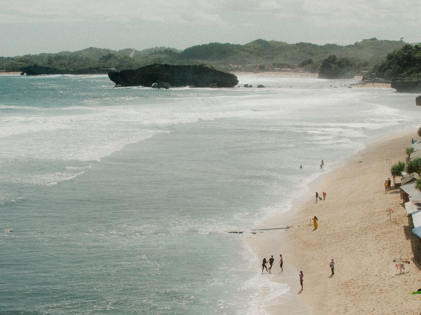 Aerial view of a serene beach in Jogja, Indonesia, with people enjoying the seaside.