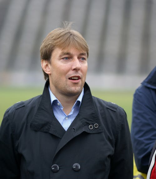 A man in a jacket and tie standing next to another man