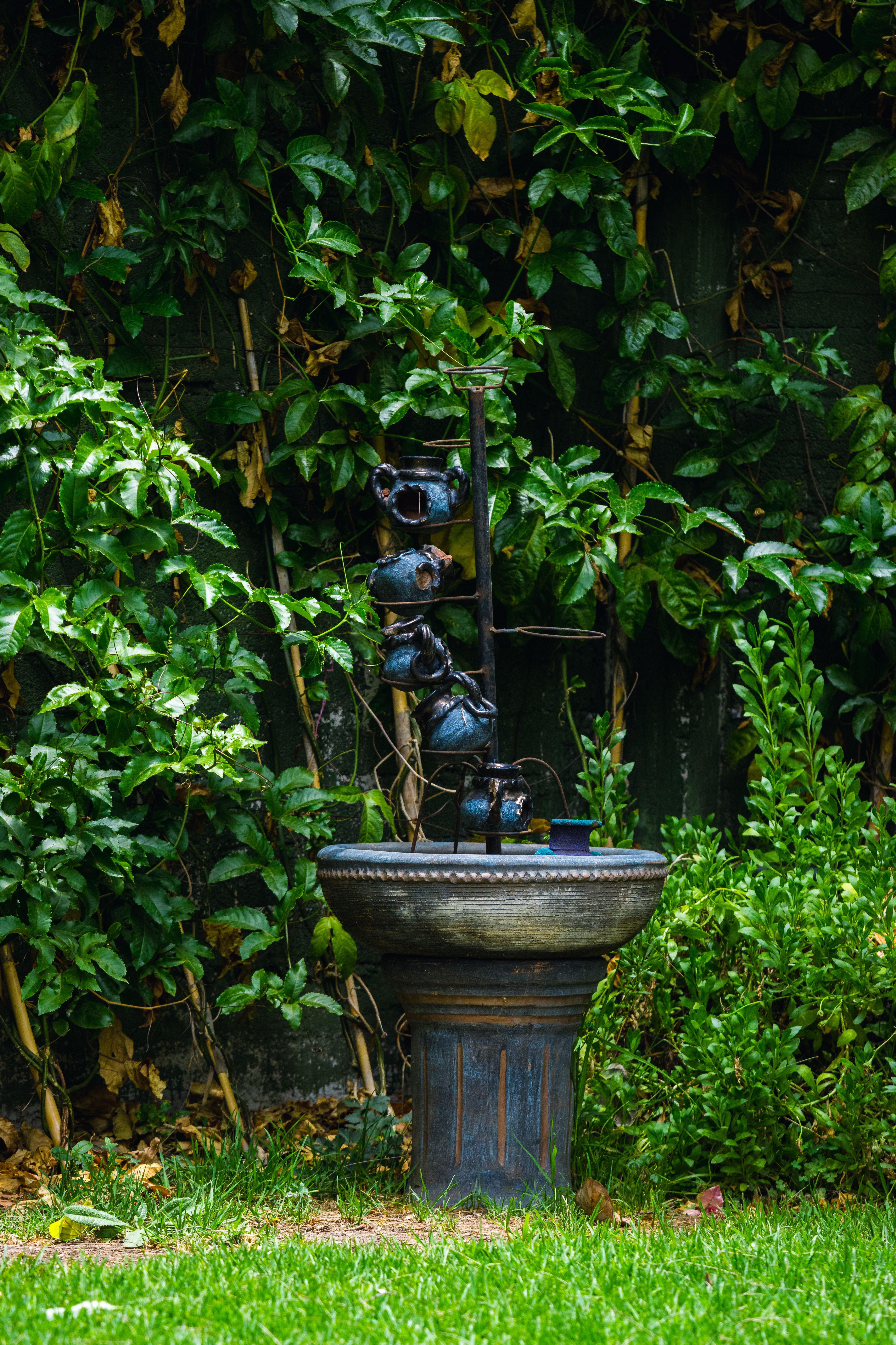 A fountain in the middle of a garden with green grass · Free Stock Photo