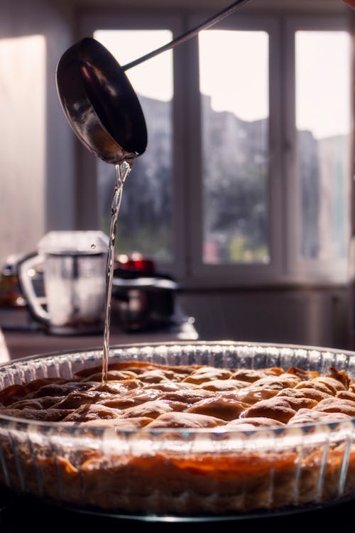 A person pouring syrup on a pie in a pan