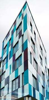 A vibrant modern building with multicolored panels in an urban setting, showcasing contemporary architecture.