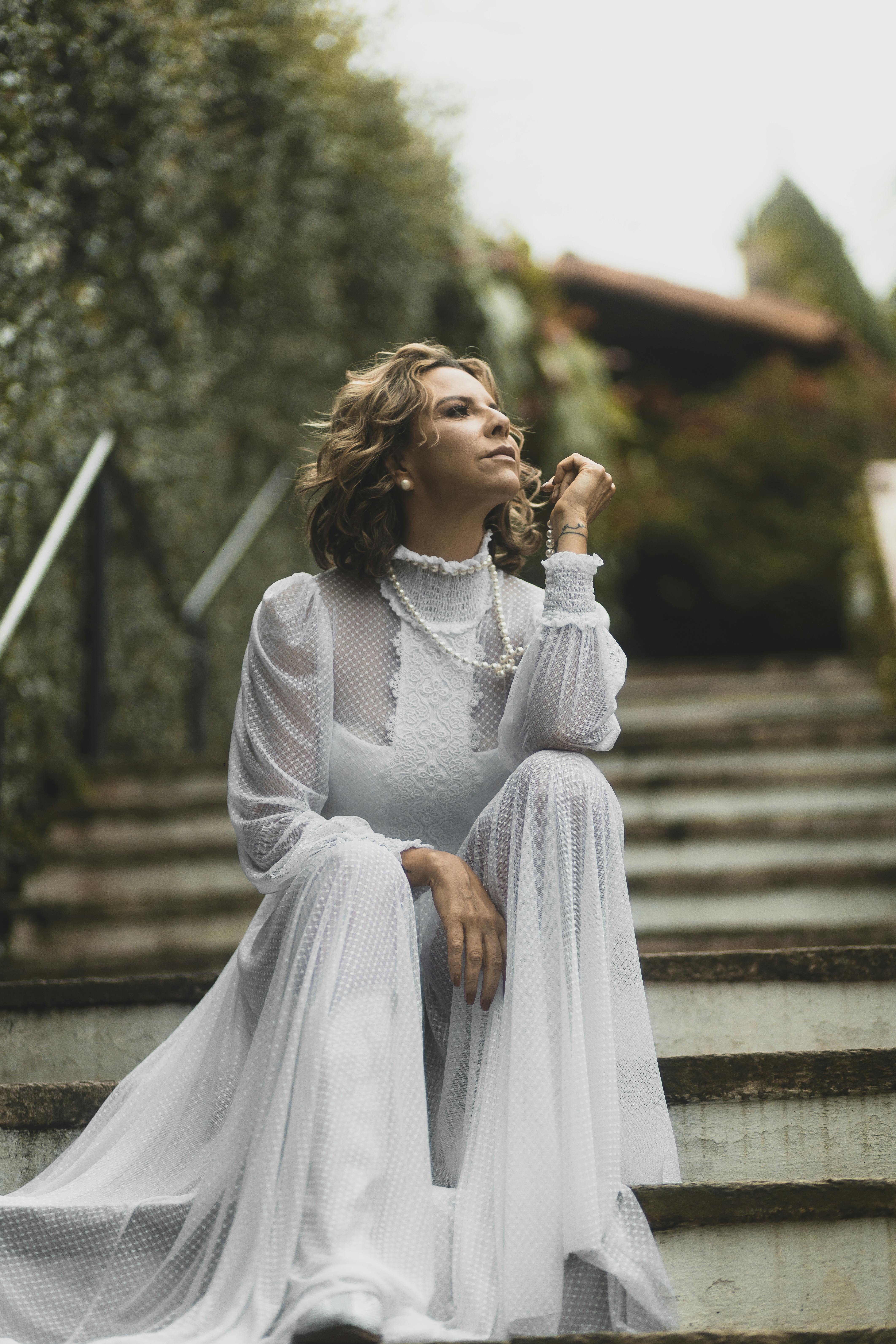 Free A Woman in a Wedding Dress Posing on Stairs Stock Photo