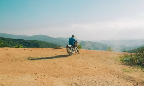 Free A motorcyclist admires the breathtaking mountain landscape from a dirt path. Stock Photo