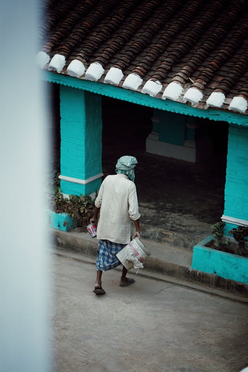 Woman with Bucket Walking towards House