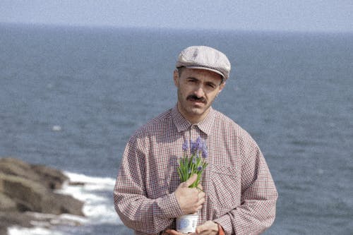Man in Shirt and with Cap Posing with Flowers