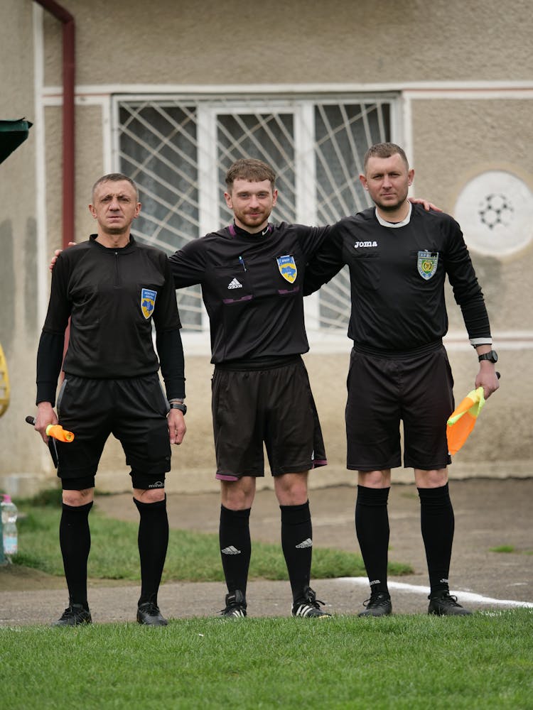 Referees In Black Jerseys On Pitch