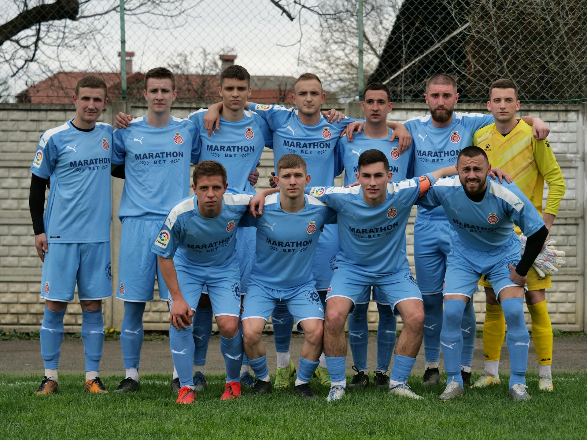 Group portrait of an amateur football team posing outdoors in blue jerseys.