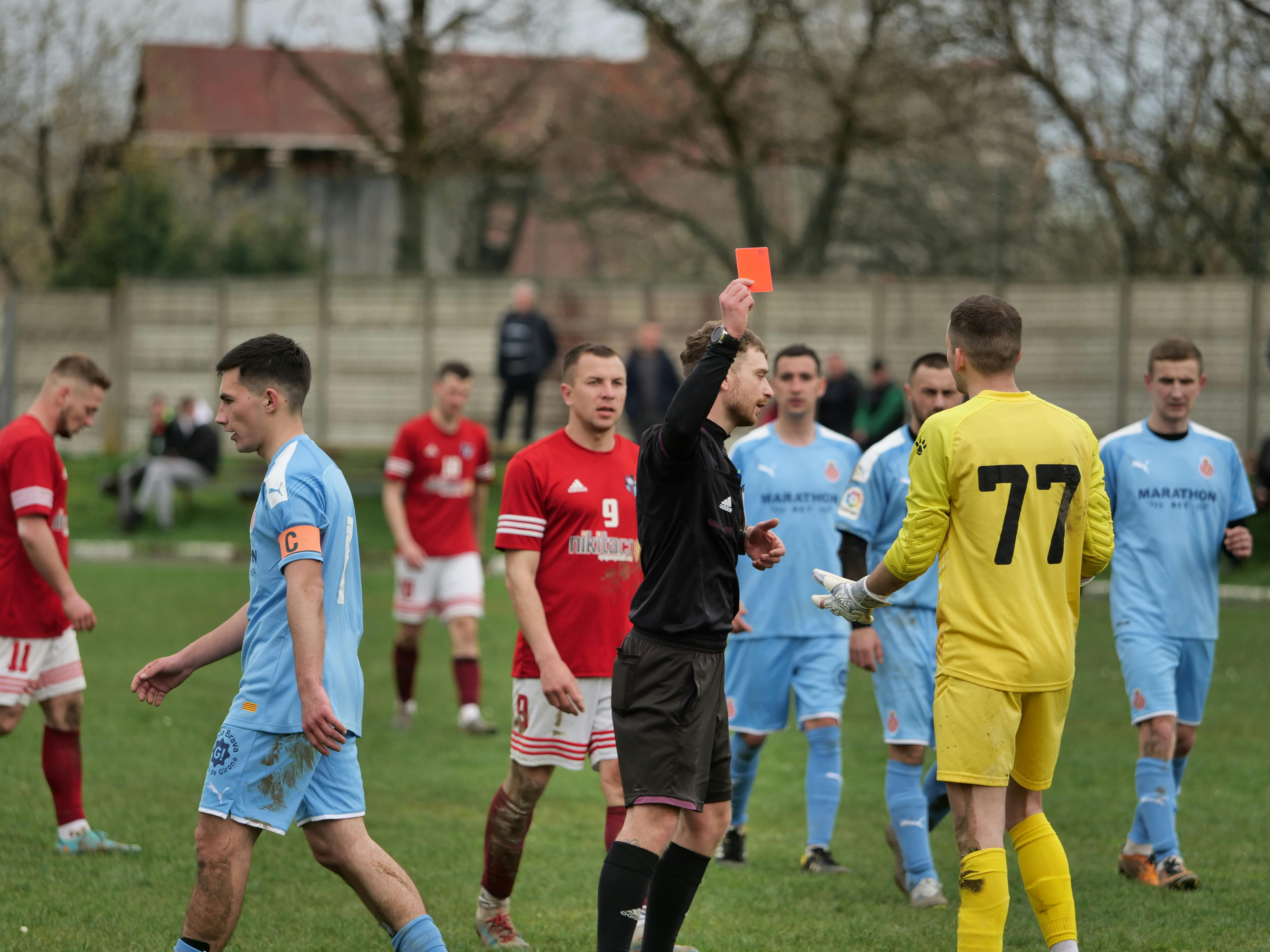 referee showing red card to goalkeeper