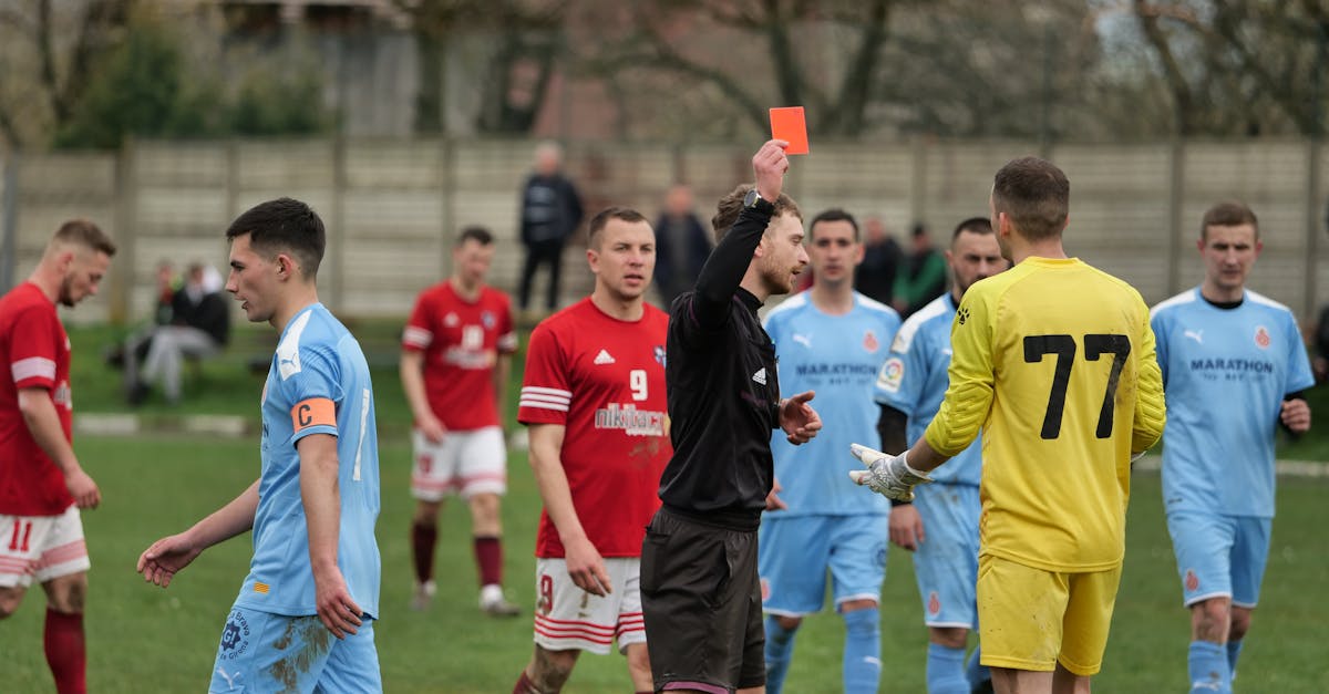 A heated moment as a referee shows a red card to a goalkeeper during a competitive soccer match.
