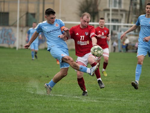 Free Stock Photo of Two footballers are fighting for the ball on the  football field