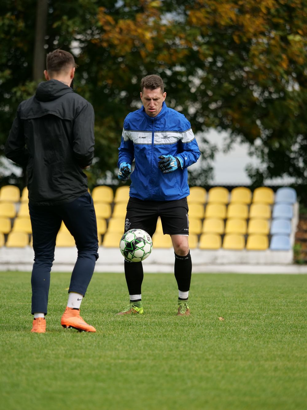 Football player training in a blue warm-up jacket and black shorts