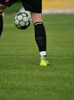 Close-up of a soccer player kicking a ball on a lush green field, focused on movement and technique.