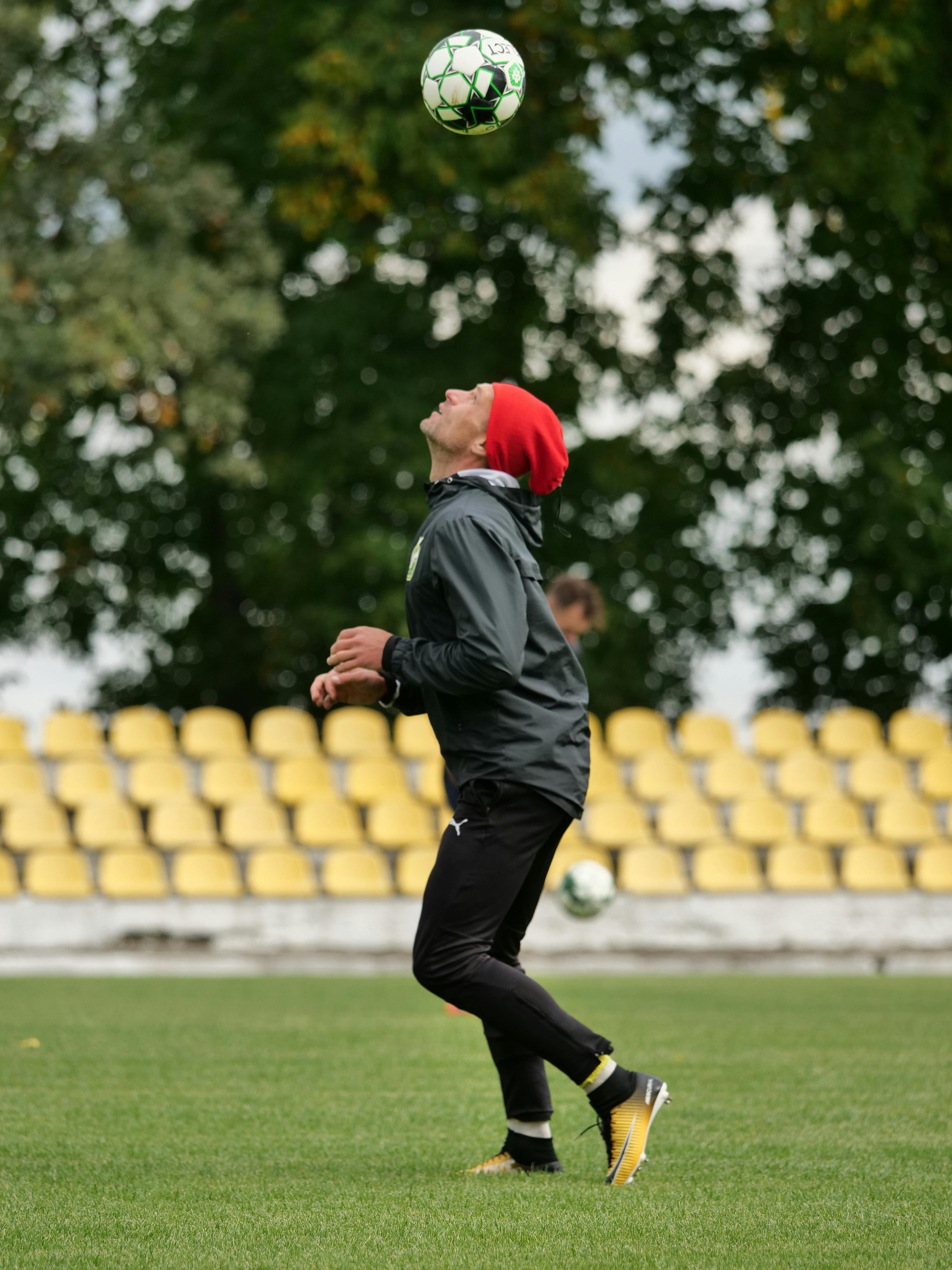 Soccer player practicing headers on an outdoor field wearing sportswear.