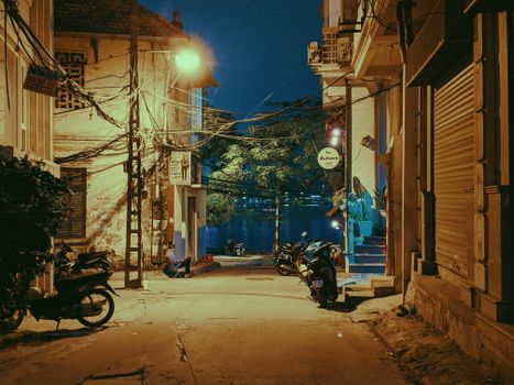Serene street scene in Ba Đình, Hanoi, Vietnam, captured at night with parked motorcycles and illuminated buildings.