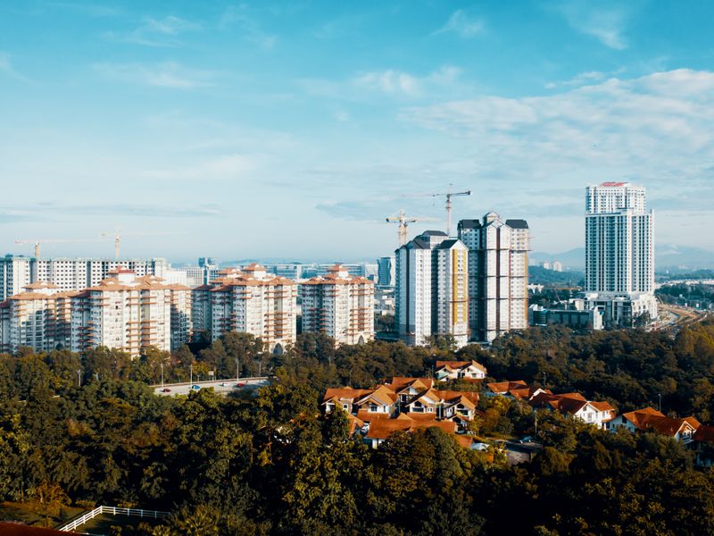 Aerial view of modern high-rise buildings rising above dense green tree cover