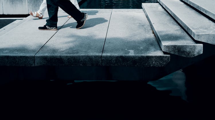 Two People Walking On Concrete Pavement