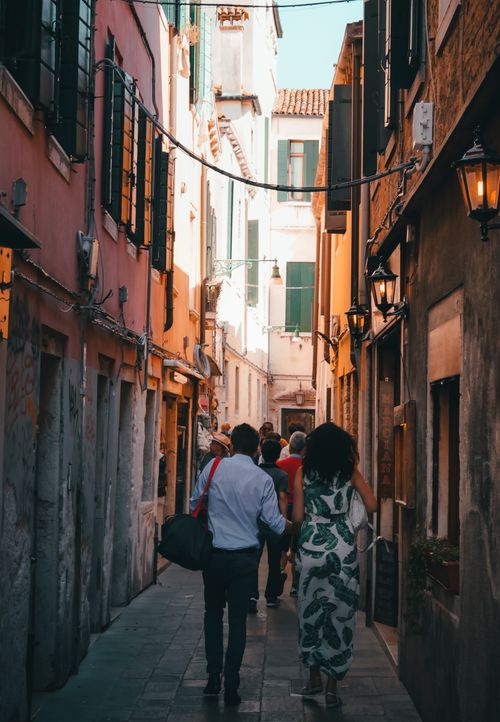 Free People exploring a narrow alleyway in Venice, capturing the historic charm and vibrant architecture. Stock Photo