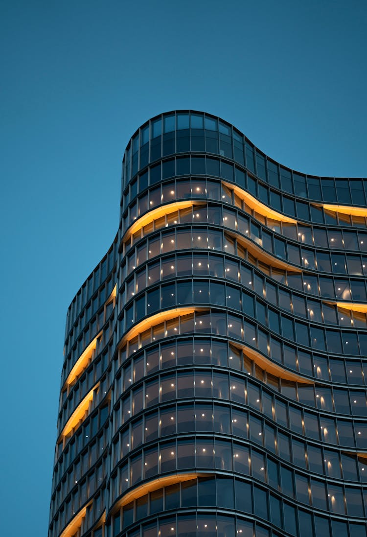 Modern Glass Skyscraper With Lights On Dark Sky Background