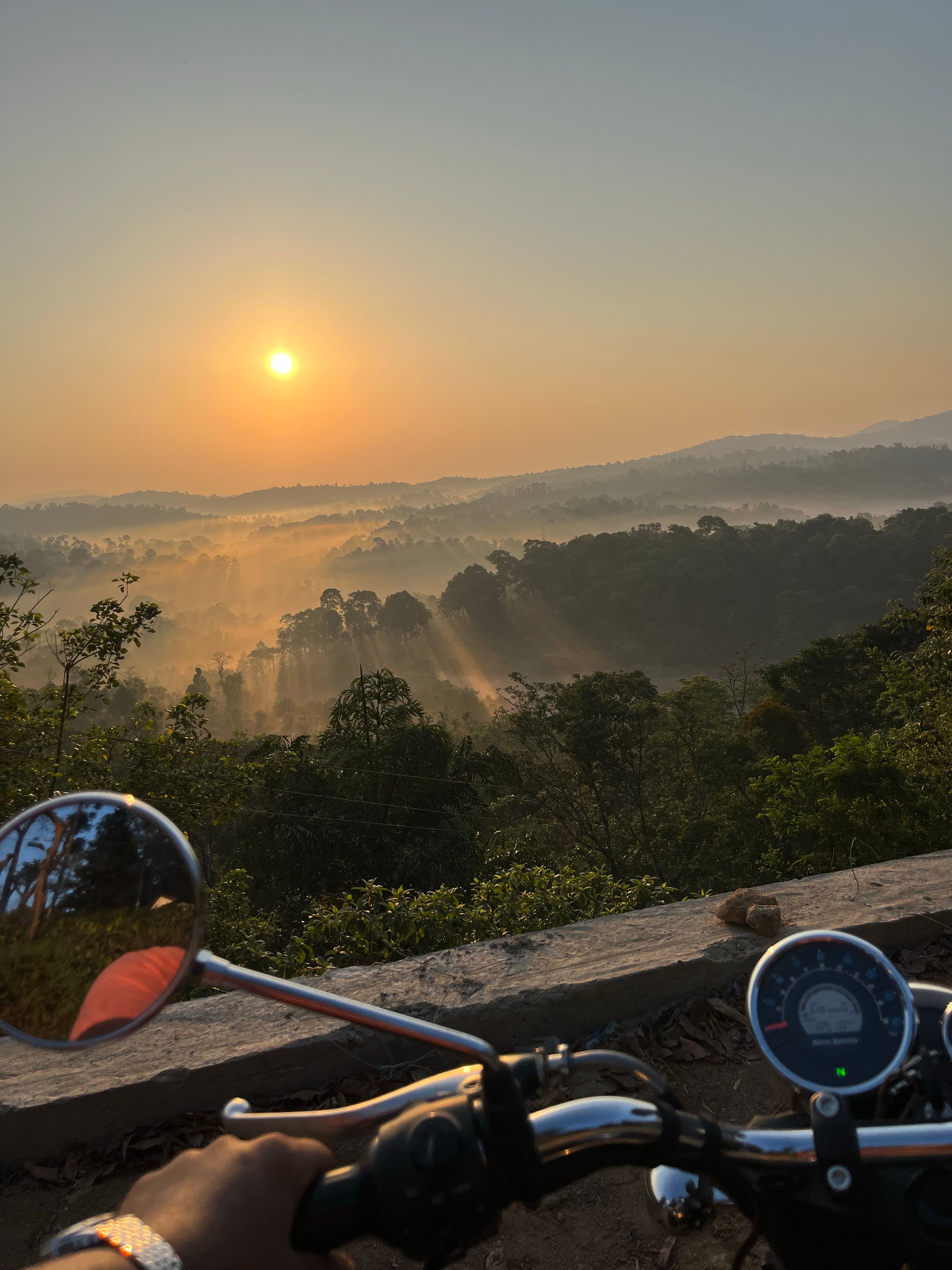 A scenic motorcycle ride at sunrise reveals mist over lush forest hills. Ideal for travel and adventure themes.