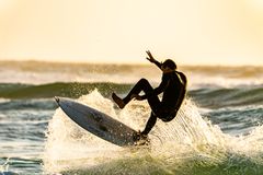 Surfer walking toward Atlantic waves on a wide Florida beach at sunrise