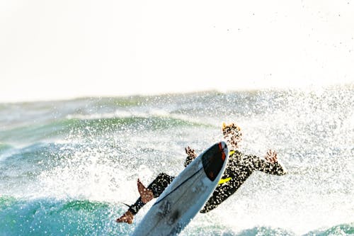 Bezpłatne Surfer Wyciera Deskę Surfingową Zdjęcie z galerii