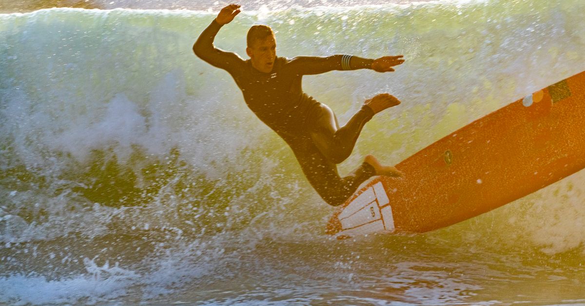 Surfer wiping out into the foam of a powerful shorebreak wave