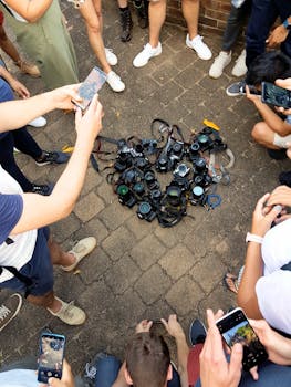 一群不同的人在人行道上用智能手机捕捉一组摄像头