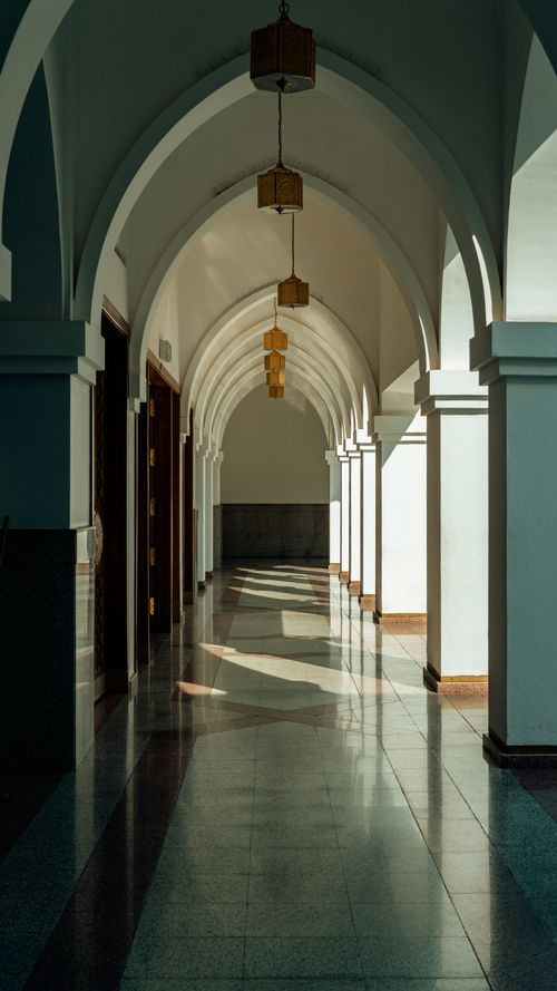 Free A serene corridor featuring arches and columns casting artistic shadows. Stock Photo
