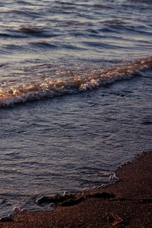 Free Gentle waves lapping the shore at sunset, capturing the peaceful twilight beach ambiance. Stock Photo