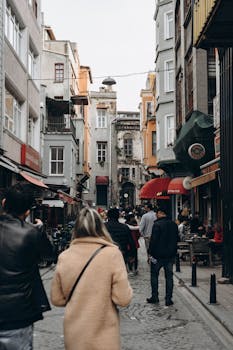 Crowded street in Istanbul with people walking between colorful residential buildings.