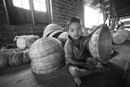 Free Black and white photo of a child with woven baskets indoors, highlighting traditional craftsmanship. Stock Photo
