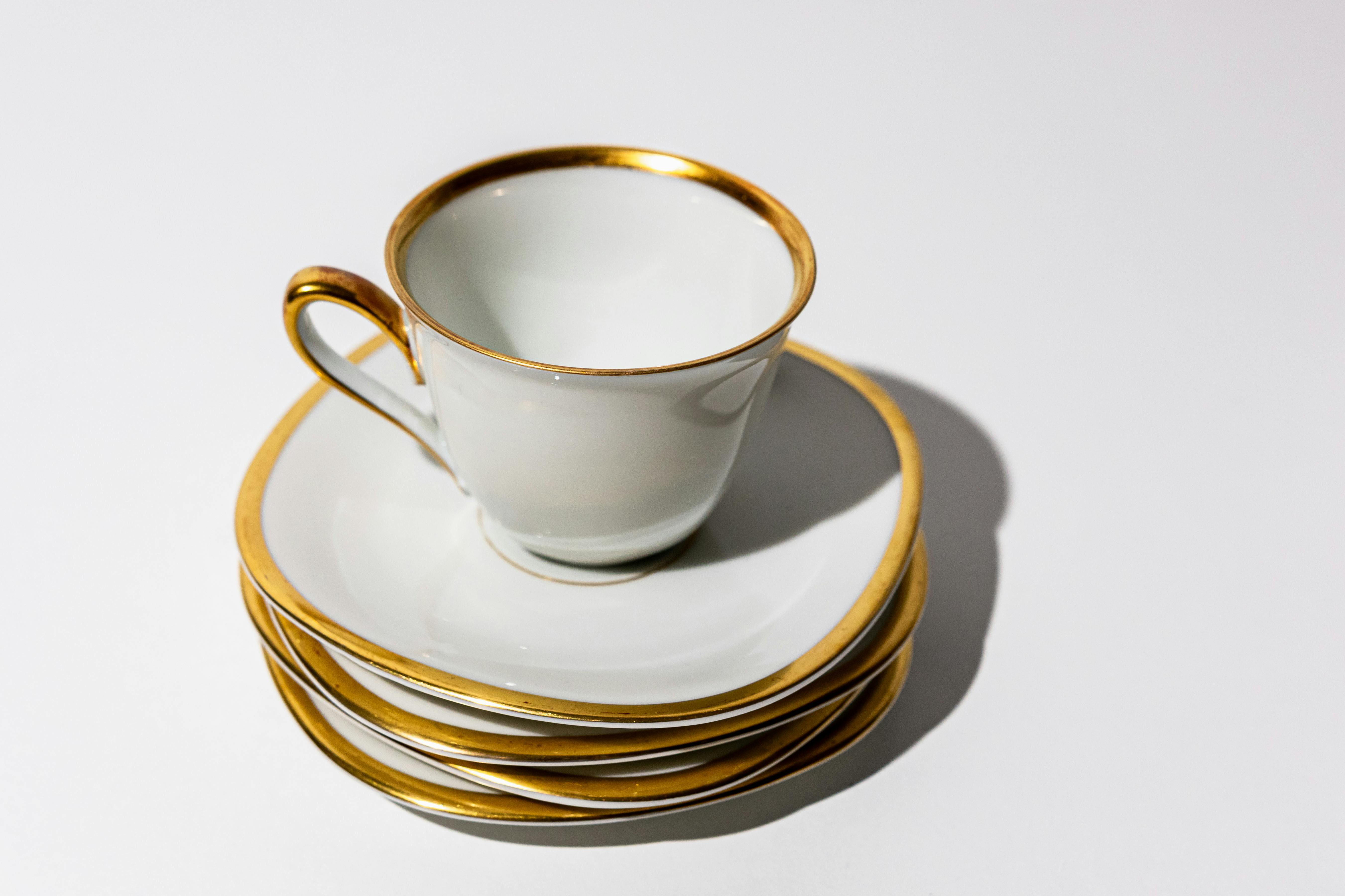 a set of four gold rimmed cups and saucers