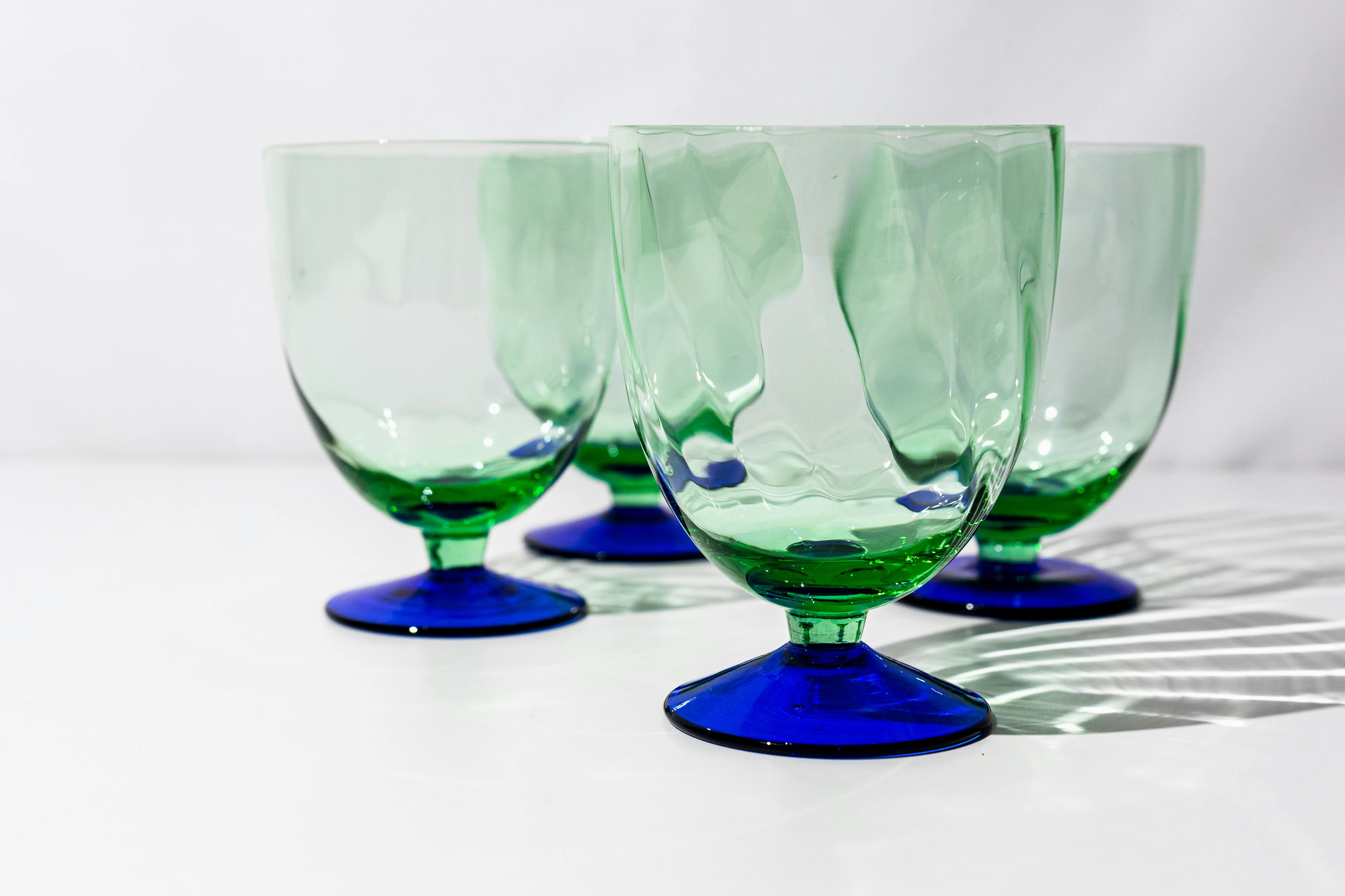 four green glass goblets with blue bases