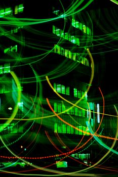 Vibrant light trails against a city building backdrop create a dynamic urban night scene.