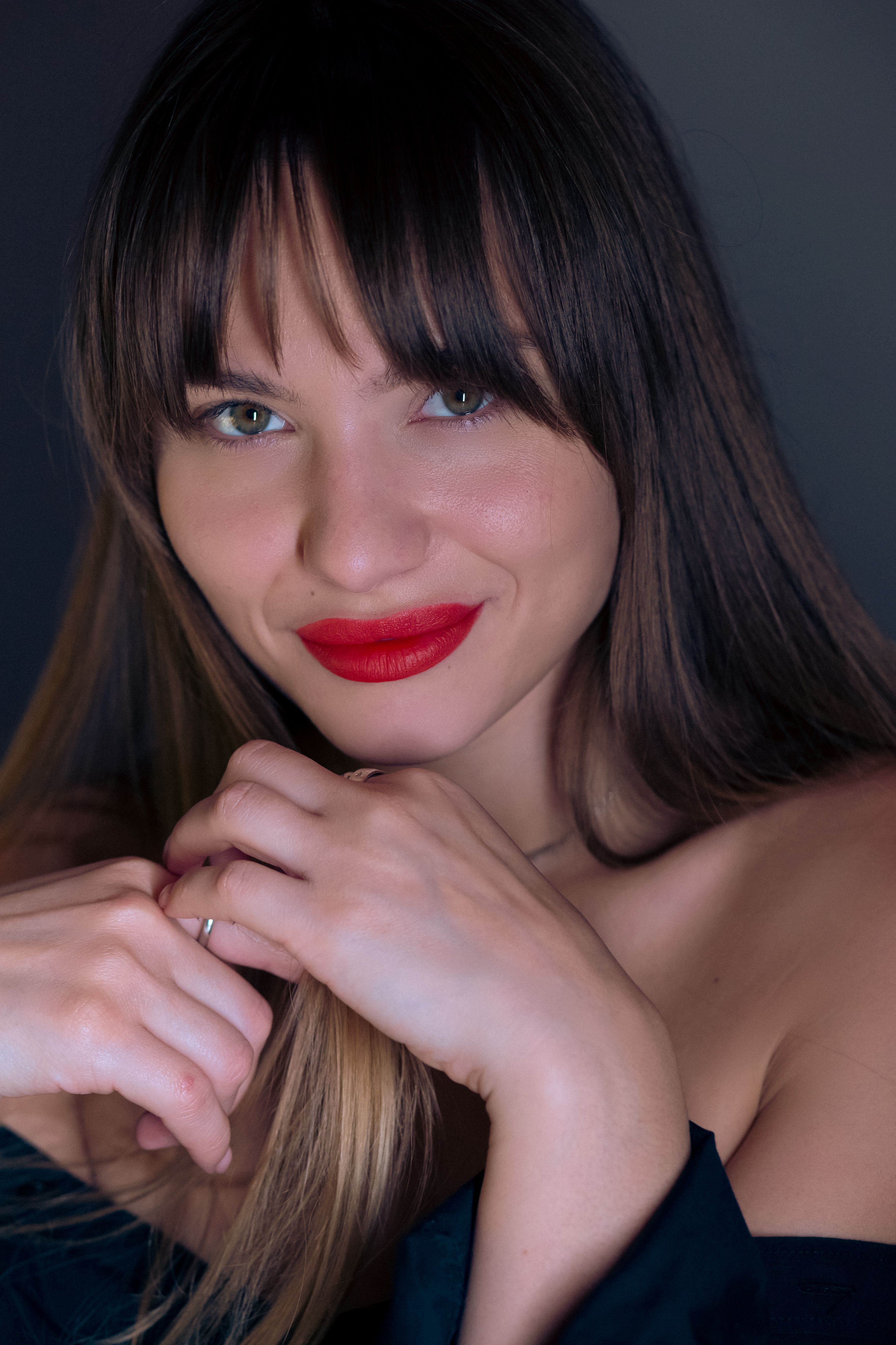 Close-up portrait of a smiling woman with red lipstick, captivating eyes, and long hair.