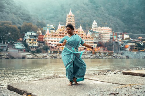 Woman in Traditional Clothing by River in Village