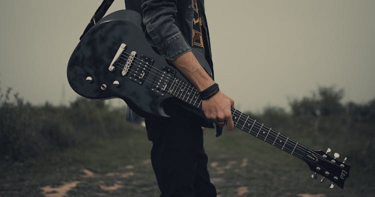 Photo Of A Guitarist With A Black Electric Guitar In A Meadow