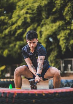 Focused athletic man with tattoos using a hammer in an outdoor workout in Managua, Nicaragua.