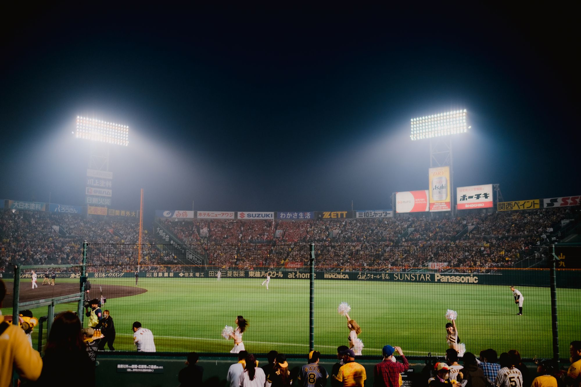 Thrilling night baseball game at Hanshin Koshien Stadium in Japan with vibrant crowd.