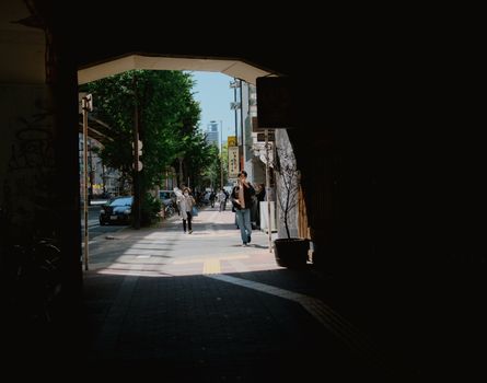 People walking through an urban street tunnel in daylight.