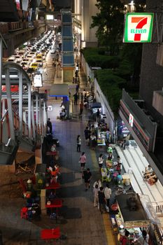 A lively urban night market scene with street food vendors and neon lights.