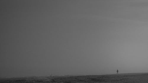 Foggy Sky over a Silhouette of a Person Standing Alone on a Beach