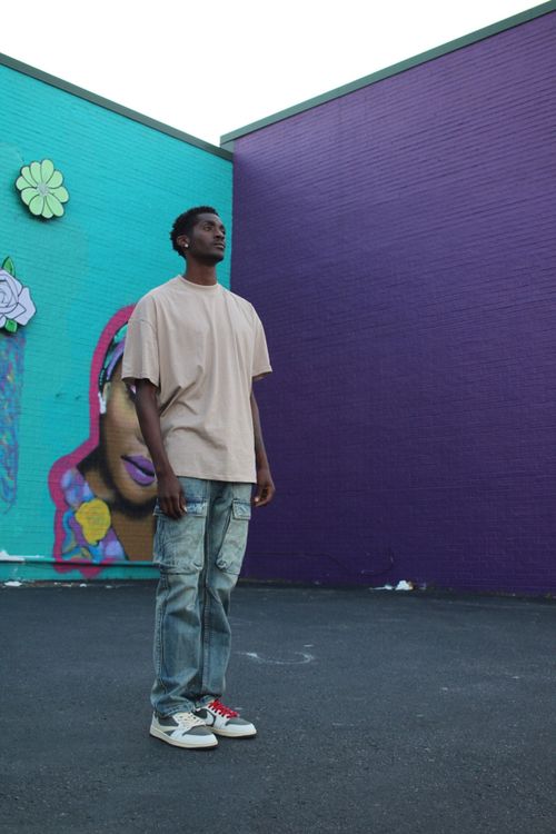 Free Man in casual attire stands in front of a vibrant mural in Nashville, showcasing urban street art and fashion. Stock Photo