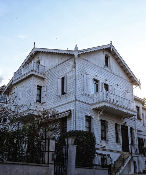 Free Elegant white wooden house featuring traditional balconies under a clear sky. Stock Photo