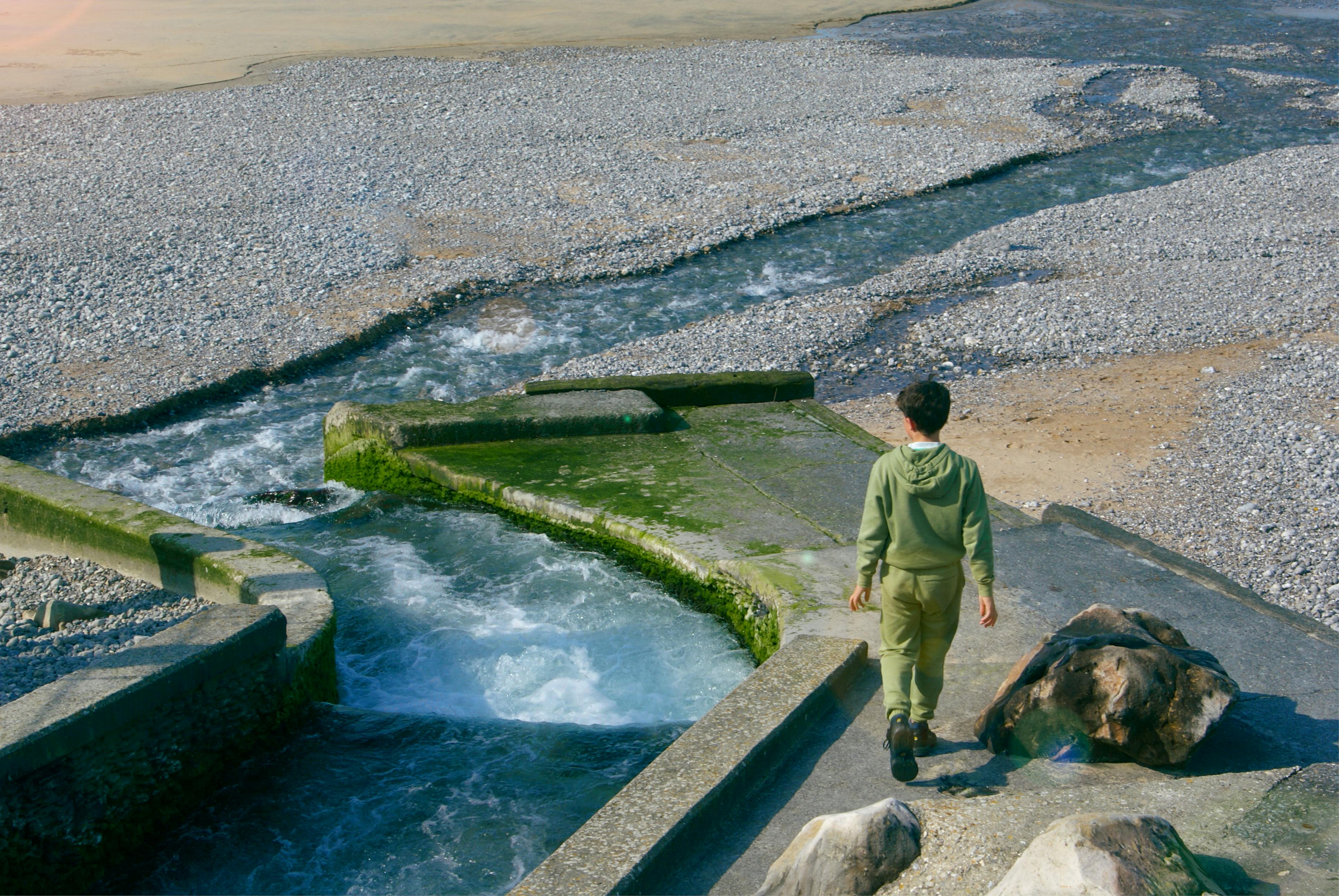 A teenager walking beside a stream in Veules-les-Roses, Normandie, France.
