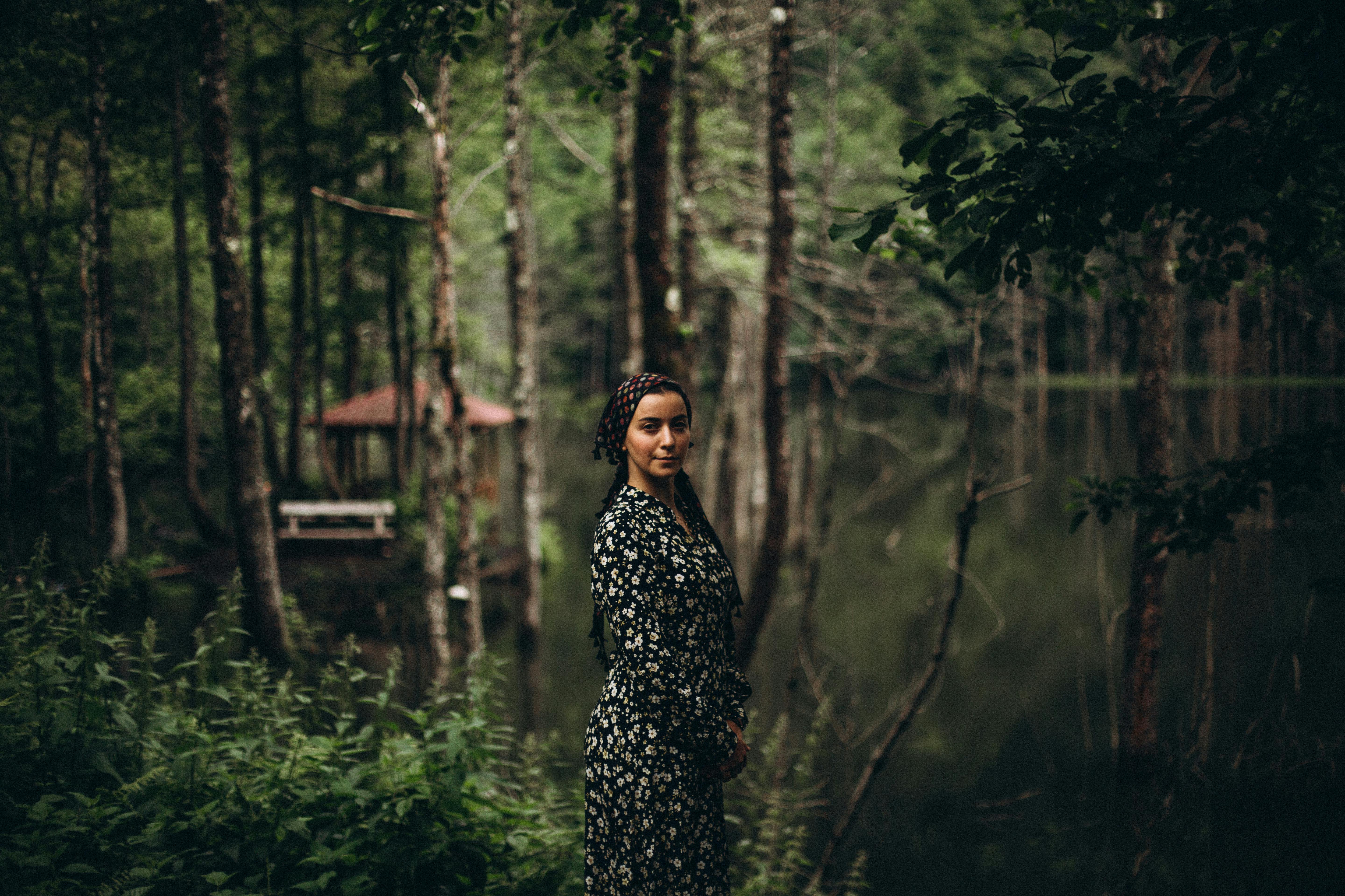 a woman standing in front of a lake in the woods