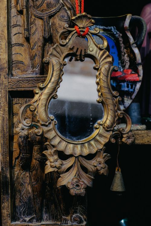 Free An antique mirror with intricate carvings and a hanging bell, showcasing vintage charm. Stock Photo