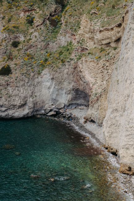 A breathtaking view of eroded cliffs meeting emerald green sea water.